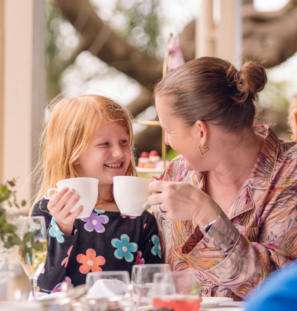 Parent and child smiling at one another holding teacups