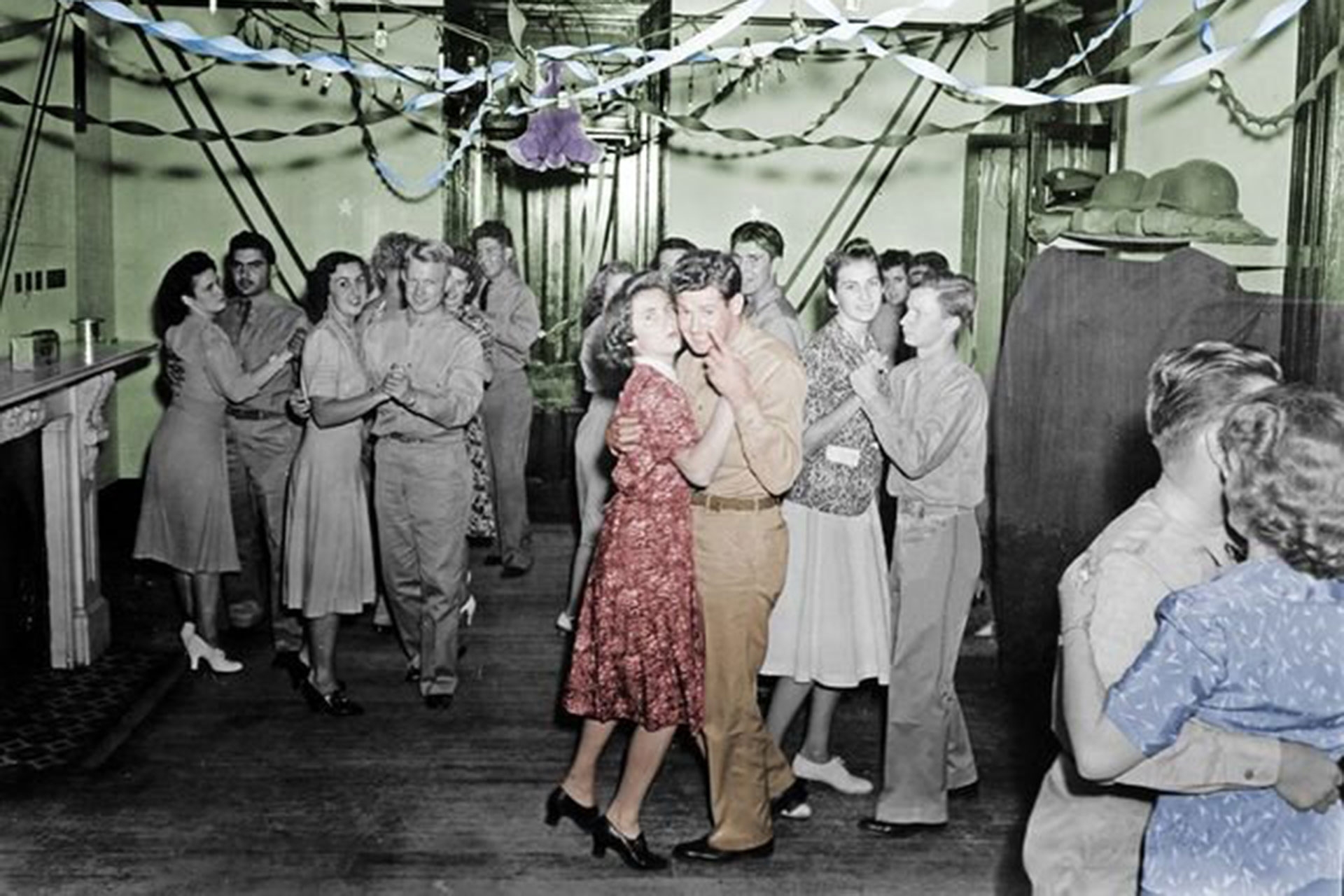 Colourised black and white photo of soldiers dancing with civilians in casual dress in Newstead House during the War Years