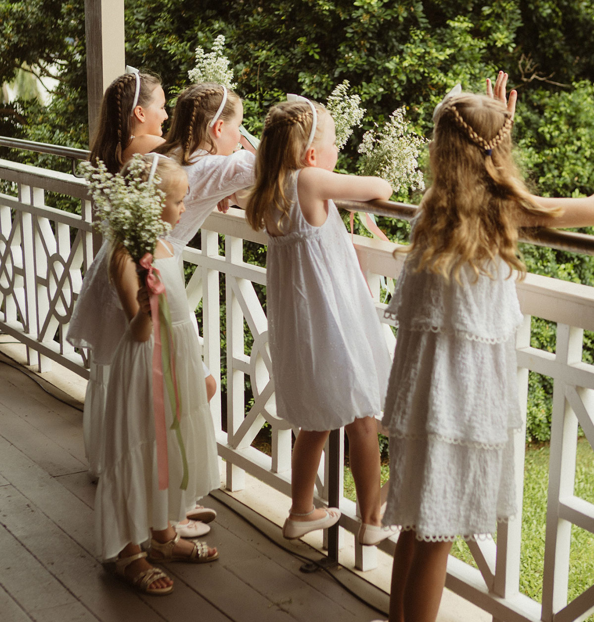 Five flowergirls in white dresses on the verandah of Newstead House facing outside