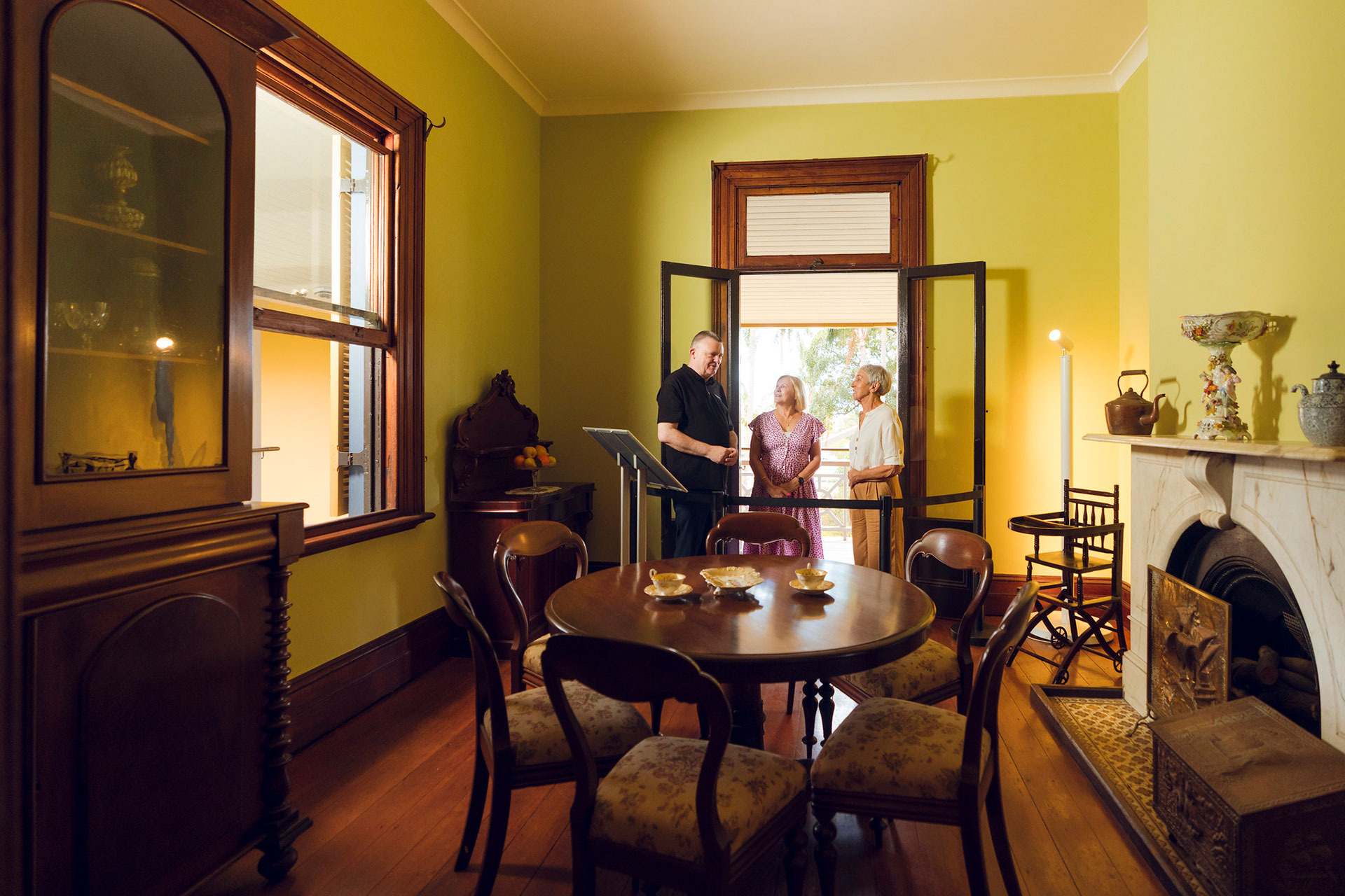 Two people and a tour guided in the Breakfast Room of Newstead House furnished with historial period items