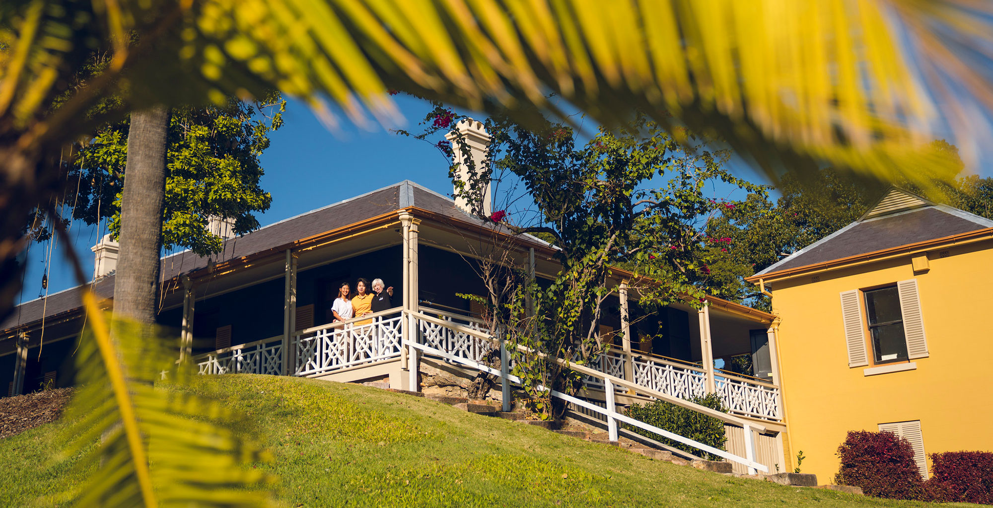 Tour guide on the veranda at Newstead House showing a young couple the house