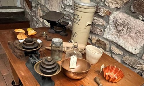 Various kitchen tools and storage vessels from the Victorian era on a table